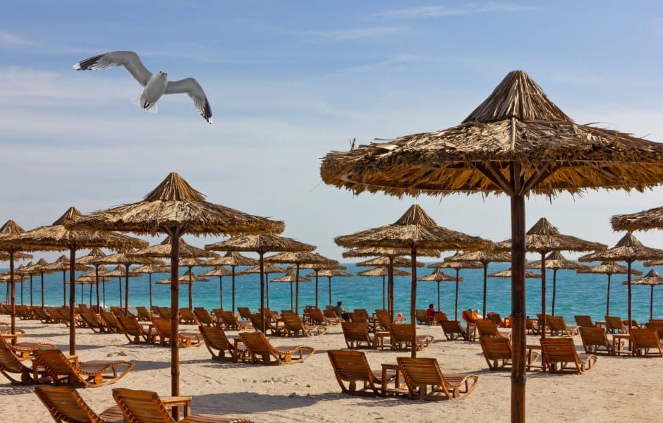 Photograph of a beach on Yas Island, with sun loungers and umbrellas lining the sand.