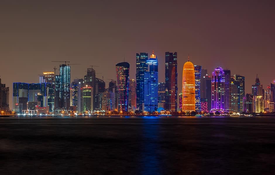 doha corniche at night with skyscrapers along the shoreline