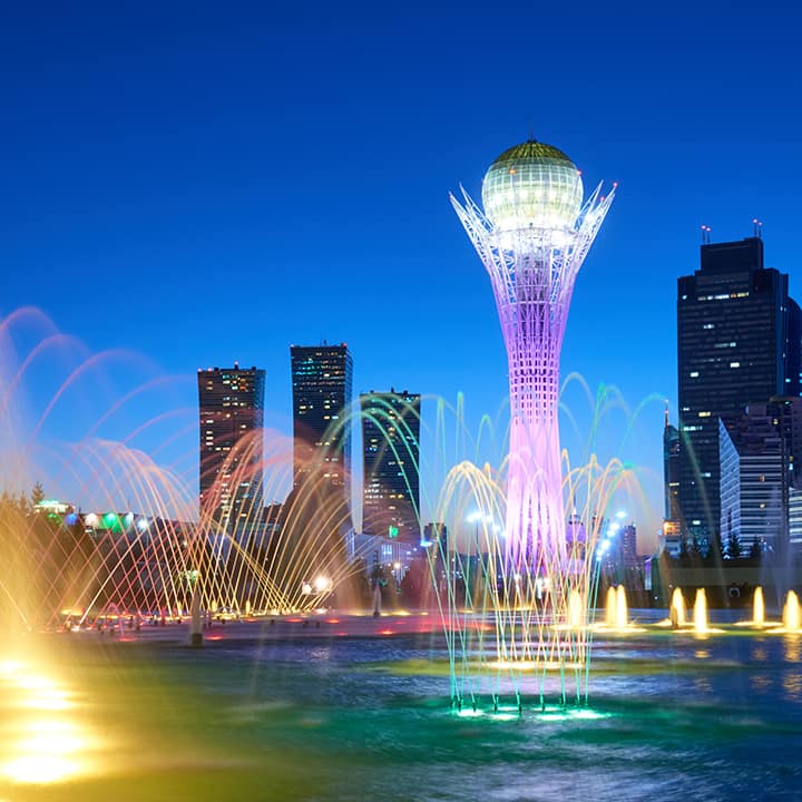 skyline and water fountain display at night in astana