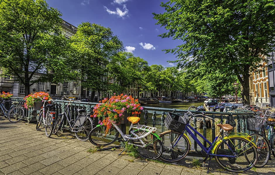 bicycles parked on bridge over canal in amsterdam