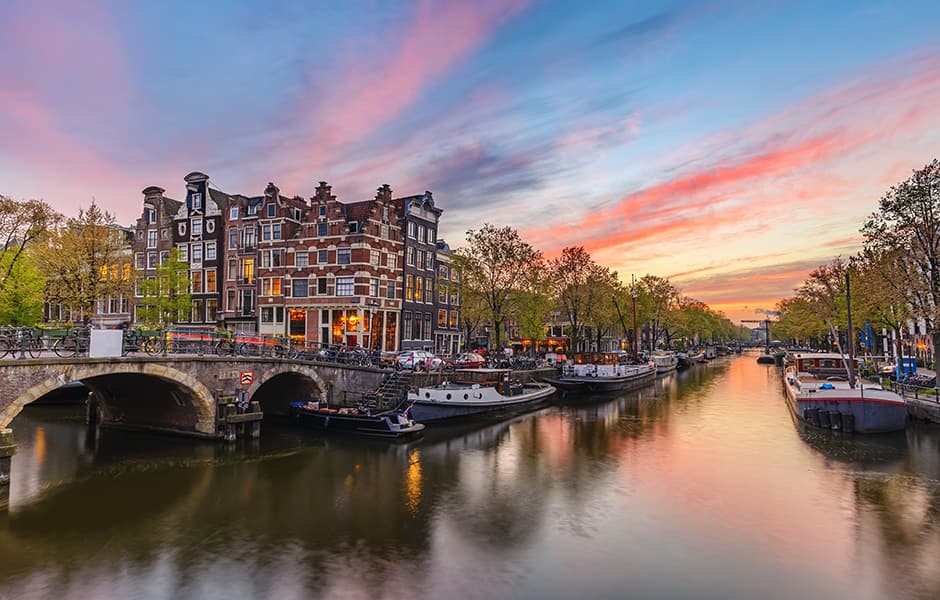 city skyline with dutch houses and canal at sunset in amsterdam