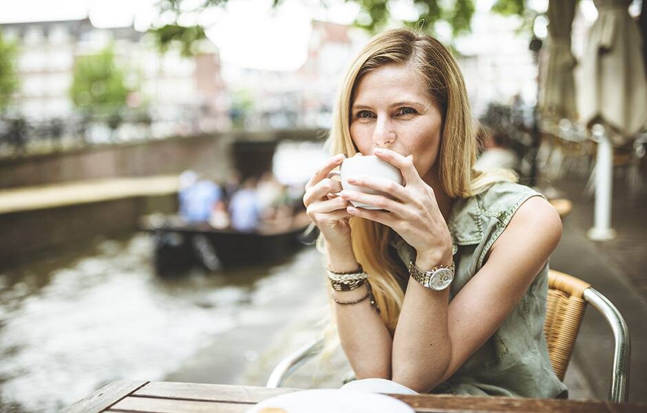 lady sitting at cafe with coffee along the canal