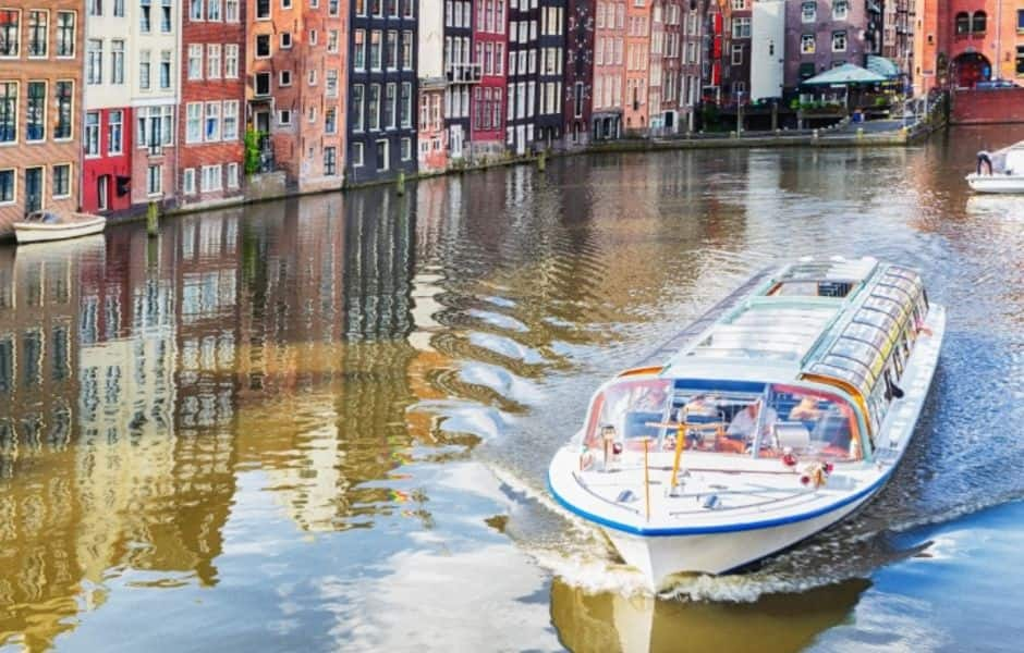 boat passing under a bridge on a canal in amsterdam 