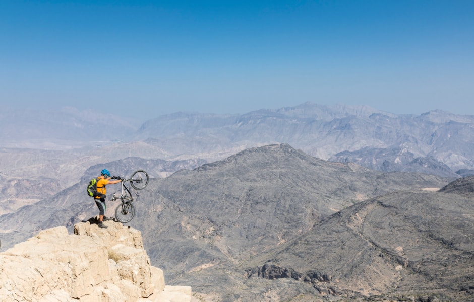 mountain biker posing on the edge of the hajar mountains in oman