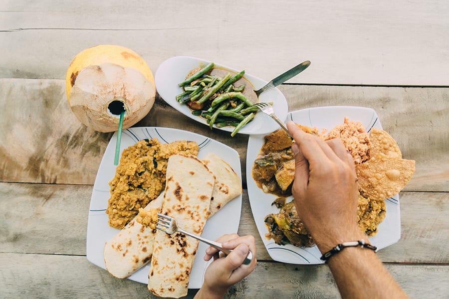 people eating a sri lankan dhal curry with vegetables and paratha