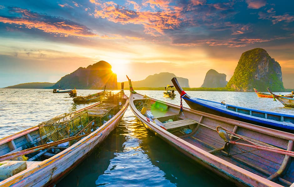 beautiful sunset at tropical sea with boats with islands in the background of thailand