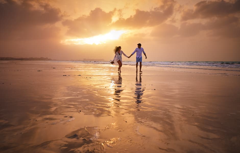 a couple walking along the beach at sunset abu dhabi