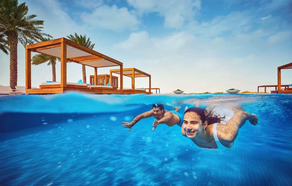 a couple swimming in the pool at saadiyat beach club in abu dhabi