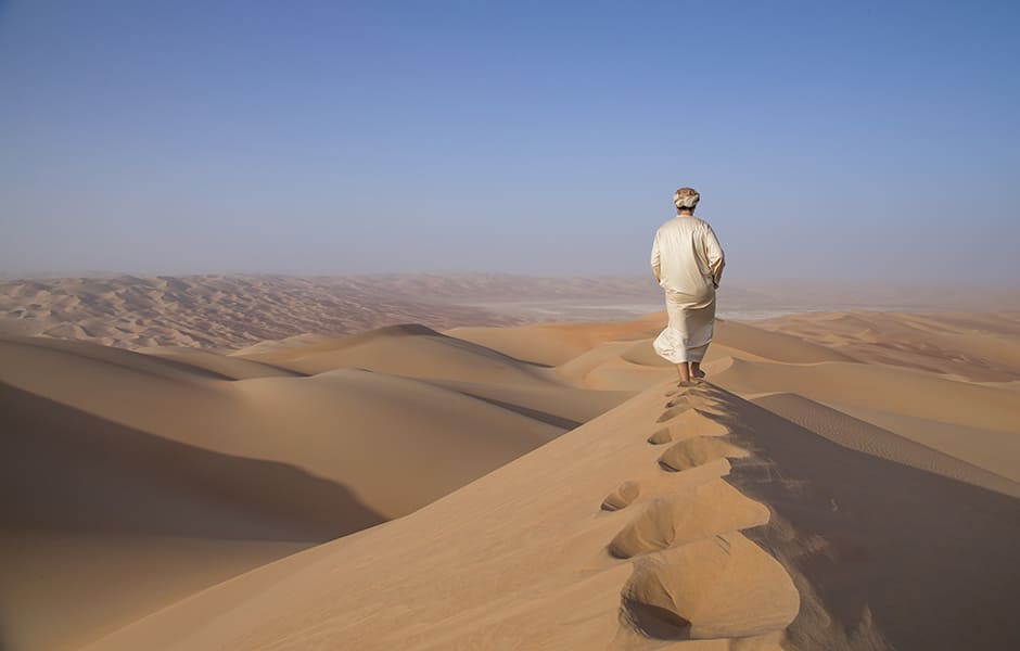 man in traditional outfit in a desert at sunrise in abu dhabi uae