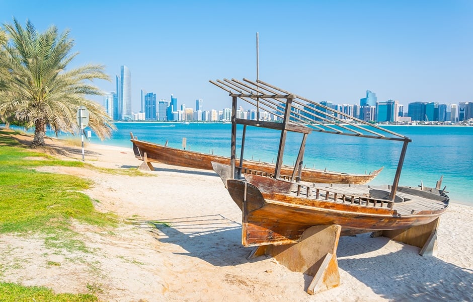 wooden boat at the heritage village in front of the abu dhabi skyline